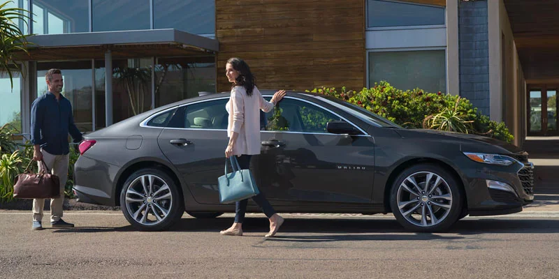 Two people standing next to their 2025 Chevrolet Malibu near Clinton Township, MI