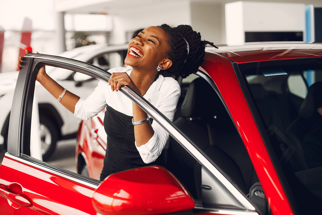Happy woman smiling in a red car.